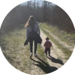 Une mère et son jeune enfant marchant main dans la main sur un chemin en forêt